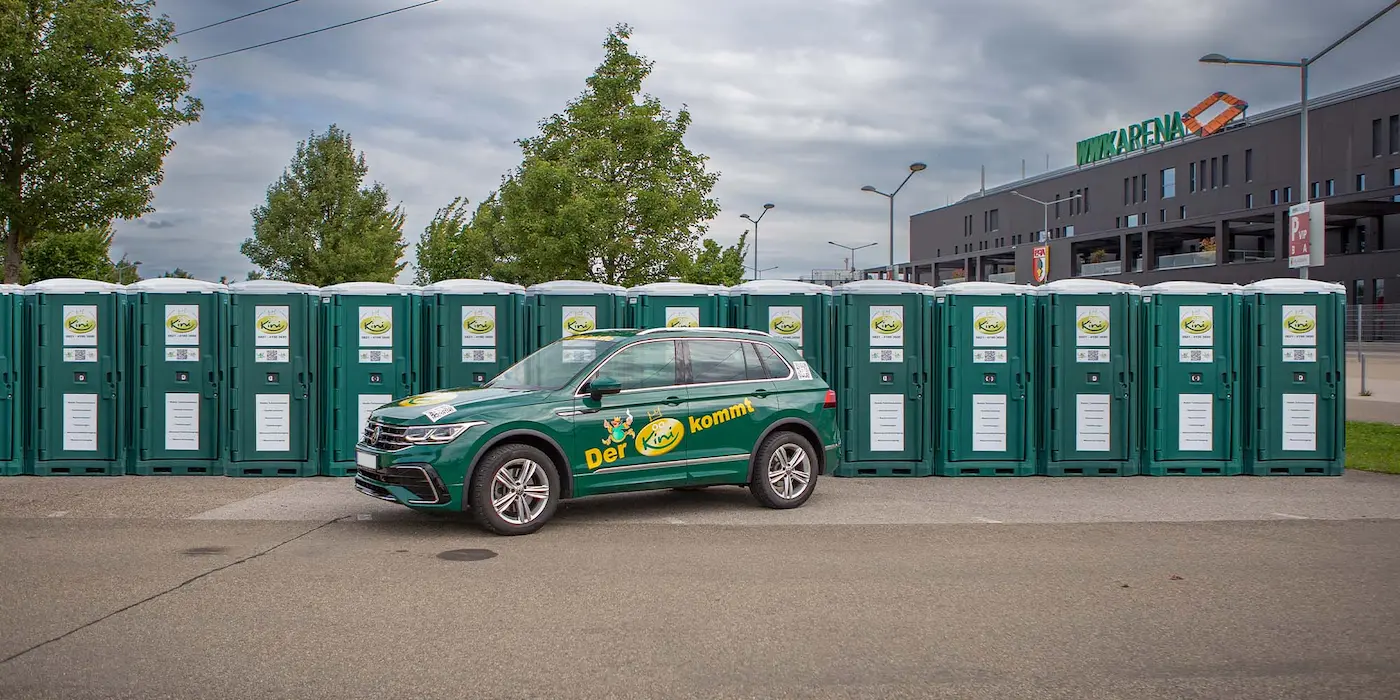 14-mobile-toiletten-auf-reisen-vw-tiguan-gruen-mit-fuehldichkini-aufdruck-vor-vielen-heisl