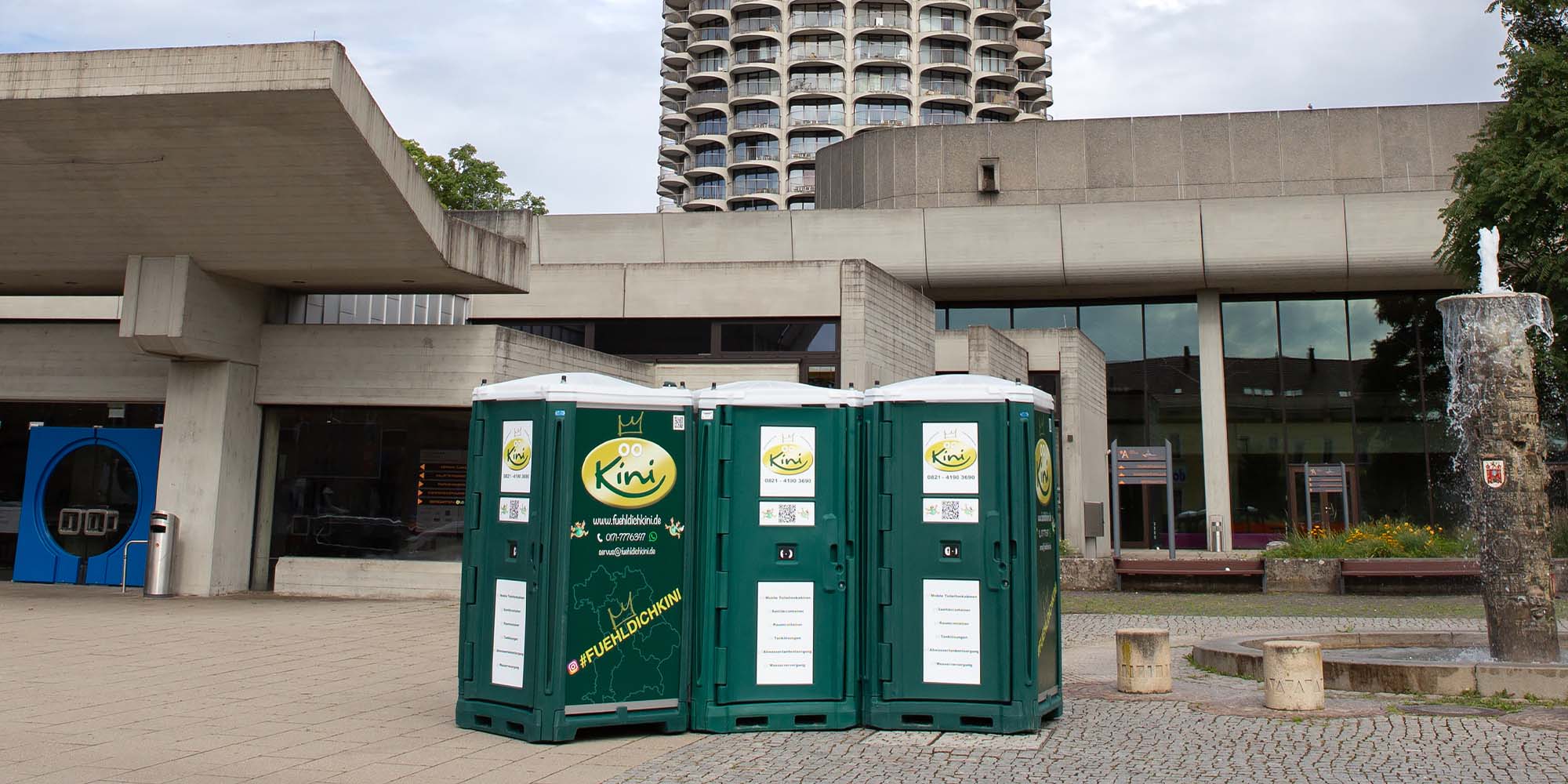 drei-gruene-dixi-toiletten-vor-gebäude